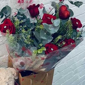 Valentines Day, six red roses with teddy bear, box of chocolates and a heart shaped balloon.