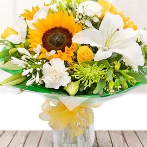 Bouquet of beautiful mix of yellow sunflowers, roses, and alstros, white carnations, and lilies with seasonal foliage