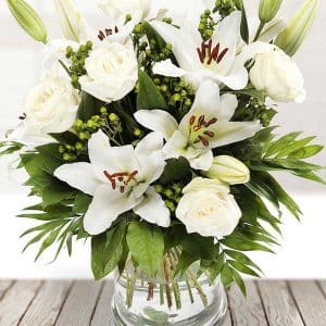 Thinking of you bouquet of white roses blended beautifully with lush lilies, green hypericum, and seasonal foliage